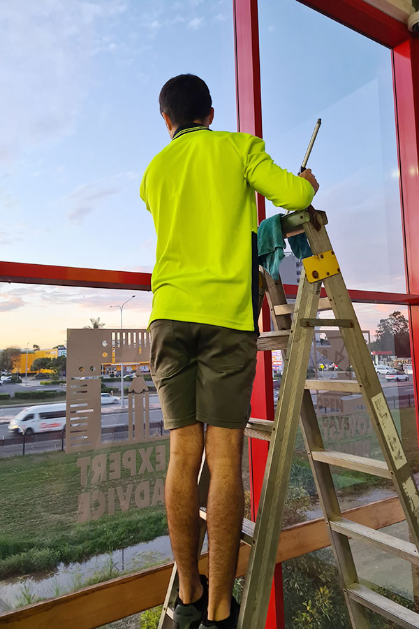 standing on ladder to clean window in brisbane